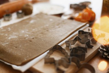 Çiğ zencefilli ekmek hamuru, metal kesiciler, tahta oklavalar, baharatlar, portakallar, köy masasında şenlikli dekorasyonlar. Zencefilli kurabiye yapmak, Noel tatili geleneği.