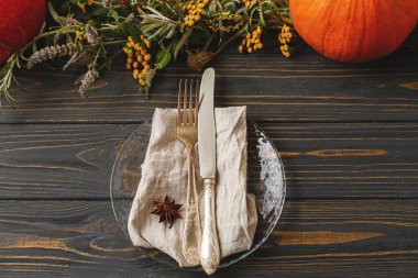 Şükran Günü sofrası. Klasik çatal bıçak takımı, keten peçete, modern cam tabakta anason yıldızı sonbahar çiçekleri aranjmanında ve kır odununda balkabağı. Düz yatıyordu. Çevre dostu