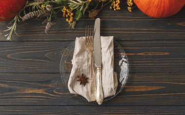 Şükran Günü ya da düğün sofrası, çevre dostu doğal düzenleme. Kaliteli çatal bıçak takımı, keten peçete, kırsal alanda cam tabakta anason yıldızı, güz çiçeği dekoru ve balkabağı.