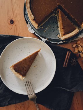 Kaliteli çatal, anason, tarçın ve ahşap masa üzerinde keten peçeteli ev yapımı balkabağı turtası dilimi. Kırsal masada kabaklı tart, Şükran Günün kutlu olsun.!
