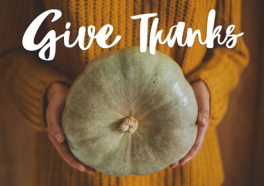 Kırsal ahşap arka planda yeşil balkabağı tutan sarı örülü kazaklı kadına teşekkür mesajı gönder. Mevsimler selamlar. Şükran Günü tebrik kartın kutlu olsun.