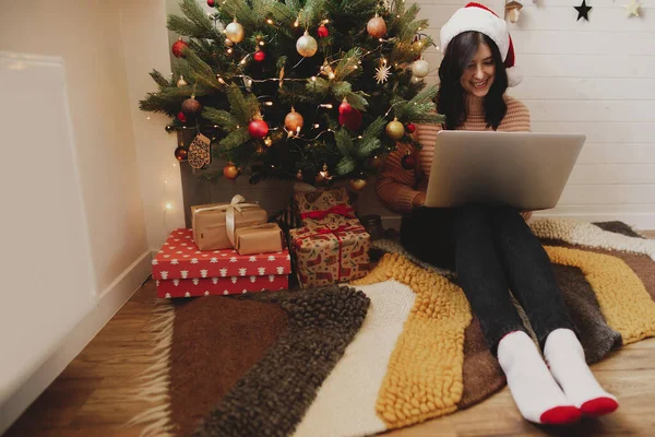 Boldog Fiatal Télapó Kalapban Laptoppal Karácsonyfa Alatt Ajándékokkal Fényekkel Ünnepi — Stock Fotó