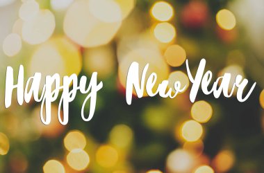 Bulanık Noel ağacına ve altın ışıklara el yazısıyla mutlu yıllar mesajı, yeşil arka planda sarı ışıklandırma bokeh. Soyut Noel arkaplanı. Tebrik kartı, modern mevsimler selamlar.