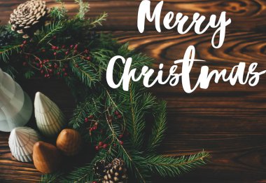 Noel 'de çelenge yazılmış küçük Noel ağaçları, böğürtlenler ve çam kozalakları kırsal ağaçlarda, noel sofrasında. Tebrik kartı, modern mevsimler selamları. İyi tatiller.