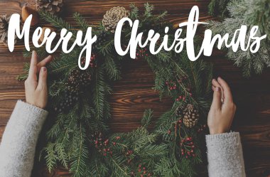 Kırsal noel çelengi üzerine yazılmış mutlu noel mesajları ahşap masada, düz bir şekilde. Tebrik kartı, modern mevsimler selamları. İyi tatiller.