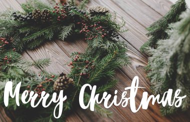 Mutlu Noeller tebrik kartı. Modern noel çelengi, kozalak ve doğal ağaç süslemeleri üzerine yazılmış mutlu noel metinleri. Mutlu tatiller, mevsimler selamlar