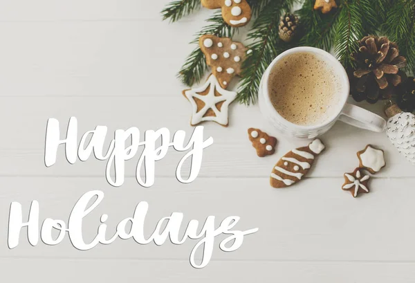ホワイトウッドのジンジャーブレッドクッキー コーヒー パインコーン モミの枝でクリスマスフラットレイに手書きの幸せな休日のテキスト グリーティングカード現代の季節の挨拶 — ストック写真