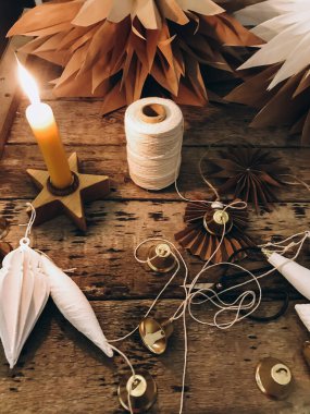 Şık bir Noel kâğıdı yıldızı, melek, kırsal ahşap masa üzerinde yıldız mumu ve metal makaslı beyaz süsler. El yapımı tatil dekorasyonu, karamsar bir görüntü