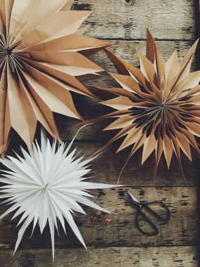 Kırsal ahşap masada metal makaslı, üst manzaralı, şık bir Noel kâğıdı yıldızı. El yapımı tatil dekorasyonu, karamsar bir görüntü. İsveç yıldızı