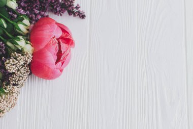 Beyaz ahşap arka planda şakayık, leylak ve gül çiçekli şık bir buket. Anneler Günü ve Sevgililer Günü konsepti kutlu olsun.