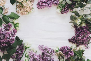 Leylak ve güller bembeyaz ahşap zemin üzerinde düz bir çerçeve ve metin için yer vardı. Anneler Günü ve kadınlar günü tebrik kartı şablonu. Çiçek kompozisyonu düzdü