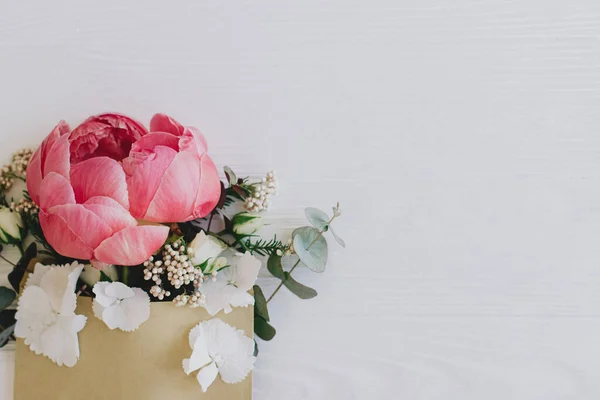 白い木の上のクラフトエンベロープから成長する牡丹 白い花やユーカリ テキストのためのスペースとフラットレイアウト 創造的な花の挨拶カードまたはメッセージの概念を送る 幸せな母の日とバレンタイン — ストック写真