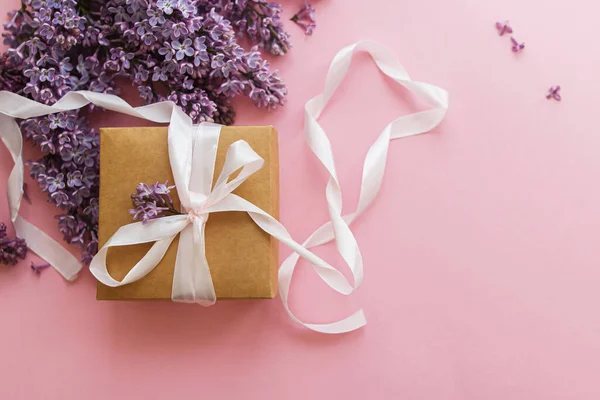 ピンクの紙にライラックの花やギフトボックス スタイリッシュなフラットレイアウト 幸せな母の日と女性の日の概念 春の花グリーティングカード クラフトプレゼントとリボンと紫ライラックブーケ — ストック写真