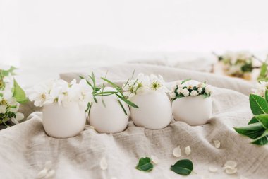 Çiçekli taçlarda doğal yumurtalar keten kumaş arka planda çiçek açan bahar dalları ve yumuşak ışıkta beyaz taç yaprakları. Mutlu Paskalyalar! Çevre dostu organik tatil konsepti.