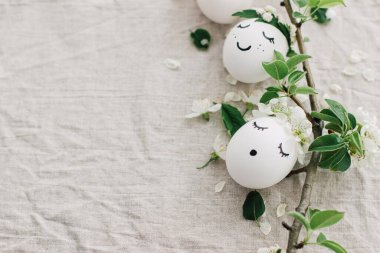 Mutlu Paskalyalar! Çiçek desenli keten kumaş, çiçek yaprağı ve yeşil yapraklı komik yüzlü doğal yumurtalar. Çevre dostu tatil konsepti. Metin için boşluk