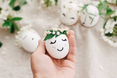 Paskalya yumurtası, çiçekli çelenk içinde uyuyan yüzü yumuşak ışıkta doğal yumurta ve keten kumaşın üzerinde taç yaprakları. Mutlu Paskalyalar ve Paskalya Avları konsepti! Metin için boşluk