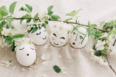 Mutlu Paskalyalar! Çiçek desenli keten kumaşlı, çiçekli çelenklerle süslü doğal yumurtalar, yumuşak ışıkta çiçek yaprakları ve yeşil yapraklar. Çevre dostu sıfır atık tatil kavramı