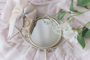 Şık bir hediye kutusu, modern mücevherler ve yumuşak kumaşta boho aynasında bahar çiçekleri. Yumuşak kadınsı bir imaj. Mutlu Kadınlar ve Anneler Günleri. Göz şeklindeki aynada alstromerya çiçekleri ve şu an