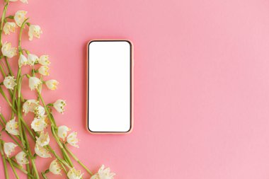 Beyaz ekranlı akıllı telefon ve pembe kağıt üzerinde bahar çiçekleri. Beyaz kar tanelerinin çiçekli yumuşak kenarı ve mesaj için yeri olan telefon şablonu. Mutlu kadınlar günü ya da anneler günü
