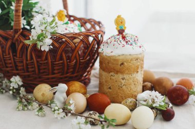 Modern paskalya yumurtaları, Paskalya ekmeği, hasır sepet, tavşan ve kır masasında açan bahar çiçekleri. Mutlu Paskalyalar! Ev yapımı kek ve doğal boyalı yumurta. Geleneksel yemek.