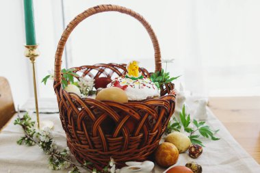 Lezzetli Paskalya yemeği, şık paskalya yumurtaları, pancar, peynir, tereyağı, jambon hasır sepetinde ev yapımı Paskalya ekmeği kırsal masada açan bahar çiçekleri, ortodoks gelenekleri. Mutlu Paskalyalar!