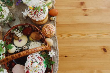 Lezzetli Paskalya yemeği, şık paskalya yumurtaları, pancar, peynir, tereyağı, jambon, hasır sepette ev yapımı paskalya ekmeği kırsal masada açan bahar çiçekleri, üst manzara. Mutlu Paskalyalar! Ortodoks