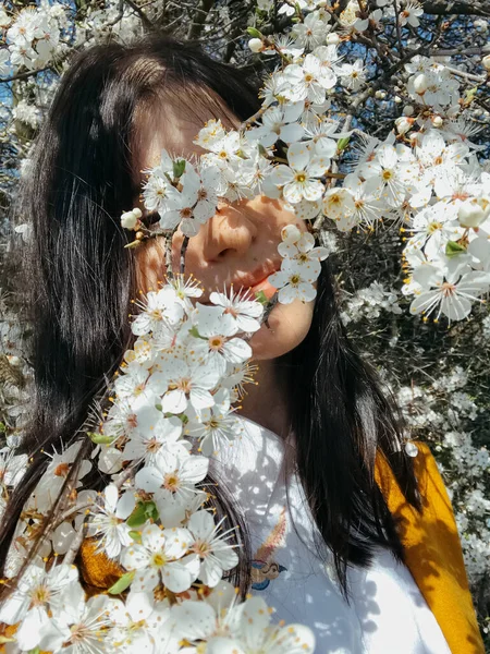 Çiçek açan kiraz dalları arasında poz veren zarif, güzel bir kadın. Şehvetli, sakin bir an. Beyaz çiçeklerle sarılmış sarı ceketli, şık, genç, esmer bir kadın.