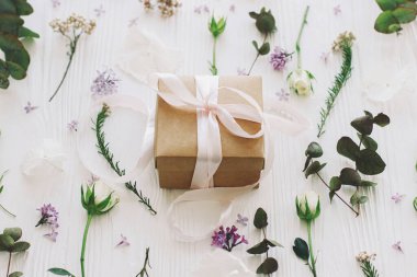 Leylak, gül, çiçek ve okaliptüs yapraklı zarif hediye kutusu beyaz ahşap arka planda. Anneler günün ve kadınlar günü konseptin kutlu olsun. Kurdele ve çiçek kompozisyonu olan bir el işi.