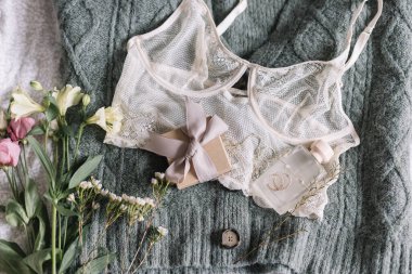 Mutlu Kadınlar Günü. Şık bir hediye kutusu, modern mücevherler, parfüm şişesi ve yatağında bahar çiçekleri olan yeşil kazaklı dantel iç çamaşırı. Yumuşak ve modaya uygun kadınsı imaj. Kadın gereksinimleri