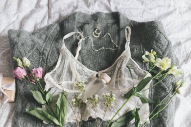 Şık bir parfüm şişesi, modern mücevherler ve üzerinde bahar çiçekleri olan dantel iç çamaşırları. Yumuşak ve modaya uygun kadınsı imaj. Mutlu Kadınlar Günü. Kadın esasları, parfüm