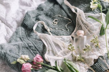 Şık bir parfüm şişesi, modern mücevherler ve üzerinde bahar çiçekleri olan dantel iç çamaşırları. Yumuşak ve modaya uygun kadınsı imaj. Mutlu Kadınlar Günü. Kadın esasları, parfüm