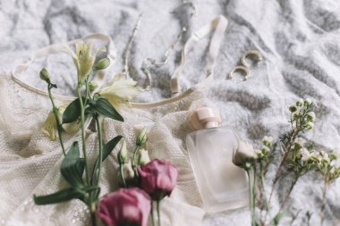 Mutlu Kadınlar Günü. Şık dantel iç çamaşırları, modern mücevherler, parfüm şişesi ve yatakta bahar çiçekleri. Yumuşak moda kadınsı imaj, ev konseptinde şehvetli ruh hali. Kadın esasları, parfüm
