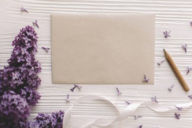 Güzel leylak çiçekleri, tebrik kartı ve beyaz rustik ahşap arka planda kurdele, metin için yeri olan düz bir yer. Çiçekli tebrik kartı şablonu. Anneler Günün kutlu olsun. Mutlu kadınlar günü..