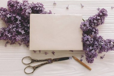 Güzel leylak çiçekleri ve klasik makas üzerindeki şık kart, beyaz kırsal ahşap üzerindeki kalem, üst manzara. Anneler Günün kutlu olsun. Mutlu kadınlar günü. Çiçekli tebrik kartı şablonu, metin için boşluk