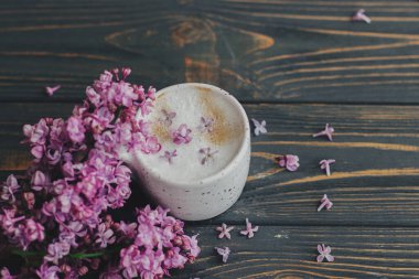 Leylak yapraklı kahve ve koyu ahşap arka planda çiçek açan bir dal ve metin için yer var. Şık fincanda taze aromatik kahve ve kır ağacında bahar çiçekleri. Sabah ritüelleri