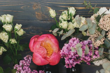 Kırsal ahşap üzerinde bahar stili taze buket kompozisyonu, çiçekli natürmort. Güzel büyük pembe şakayık, leylak, okaliptüs, koyu ahşap arka planda beyaz güller..