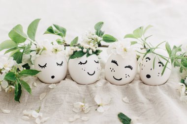 Mutlu Paskalyalar! Çiçek desenli keten kumaşlı, çiçekli çelenklerle süslü doğal yumurtalar, yumuşak ışıkta çiçek yaprakları ve yeşil yapraklar. Mesaj için yer var. Çevre dostu tatil konsepti