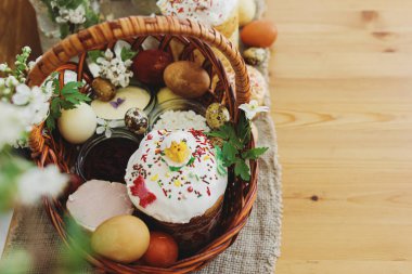 Şık paskalya yumurtaları, ev yapımı Paskalya ekmeği hasır sepetteki geleneksel Paskalya yemeği ve kırsal masada keten peçetede çiçek açan bahar çiçekleri. Mutlu Paskalyalar! Şenlikli kahvaltı.