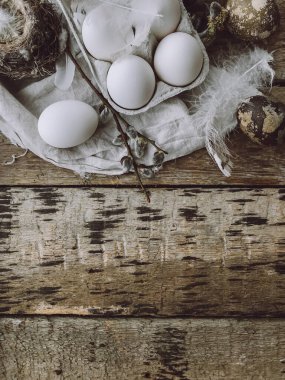 Natural easter eggs, feathers, pussy willow branches, bird nest on rustic cloth on aged wooden table. Easter rustic flat lay. Space for text. Stylish easter rural still life, brown and grey colors