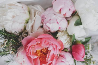 Yumuşak beyaz kumaş üzerinde güzel bir şakayık buketi. Kırsal ahşap sandalyede tül üzerinde pembe ve beyaz şakayık çiçekleri. Gelin sabahı. Üst Manzara. Anneler Günün kutlu olsun..