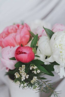 Yumuşak beyaz kumaşın arka planında güzel bir şakayık buketi. Pastel kırsal arka planda seramik vazoda pembe ve beyaz şakayık çiçekleri. Anneler Günün kutlu olsun. Modern gelin buketi