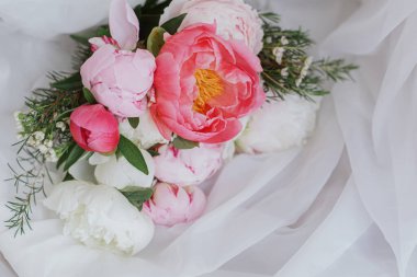 Yumuşak beyaz kumaş üzerinde güzel bir şakayık buketi. Kırsal ahşap sandalyede tül üzerinde pembe ve beyaz şakayık çiçekleri. Anneler Günün kutlu olsun. Gelin sabahı. Metin için boşluk