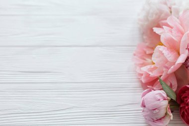 Fotokopi alanı olan beyaz ahşap üzerinde güzel, yumuşak bir kenar. Güzel pembe ve beyaz şakayıklar kır ağaçlarında çiçek açarlar. Çiçekli tebrik kartı. Anneler Günün kutlu olsun.