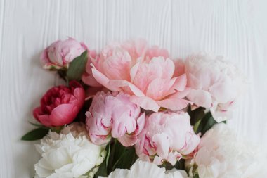 Beyaz ahşap üzerine serilmiş güzel, yumuşak şakayık buketi. Anneler Günün kutlu olsun. Güzel pembe ve beyaz şakayıklar kır ağaçlarında çiçek açarlar. Çiçekli tebrik kartı.