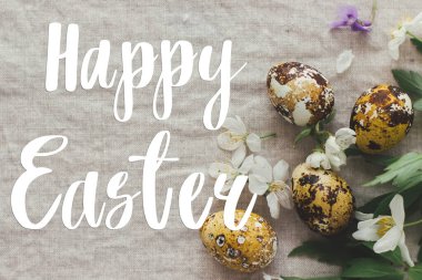 Mutlu Paskalya tebrik kartları. Modern sarı paskalya yumurtalarının üzerine el yazısıyla Mutlu Paskalya yazıları, bahar çiçekleri ve kır kumaşında çiçekler, düz yatak. Güzel kartpostallar, mevsimler selamlar