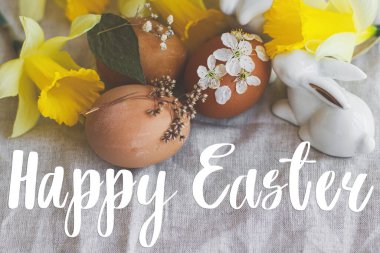 Mutlu Paskalya tebrik kartları. Paskalya yumurtalarının üzerine sarı nergis ve beyaz tavşanlı kırsal peçetedeki çiçeklerle süslenmiş mutlu paskalya mesajları. Güzel kartpostallar, mevsimler selamlar