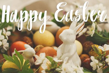 Mutlu Paskalya tebrik kartları. Modern paskalya yumurtalarının üzerine el yazısıyla yazılmış bahar çiçekleri ve çarşaf bezinde tavşan yazılı mutlu paskalya yazıları. Güzel kartpostallar, mevsimler selamlar