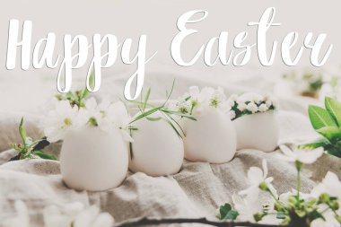 Doğal yumurtalar üzerine mutlu paskalya metinleri keten kumaşında, kiraz çiçekleri ve el yazısıyla yazılmış beyaz taçyaprakları olan hoş çiçekli çelenkler. Güzel, şık bir tebrik kartı. Mevsimler selamlar