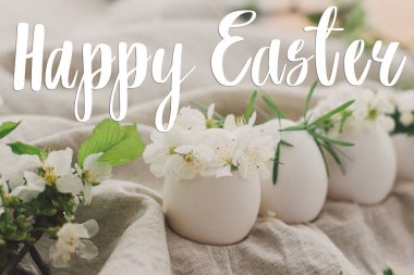 Mutlu Paskalya tebrik kartları. Kiraz çiçekleri ve beyaz yapraklarla süslü keten kumaş üzerinde doğal yumurtaların üzerine el yazısıyla Mutlu Paskalya metinleri. Güzel kartpostallar, mevsimler selamlar