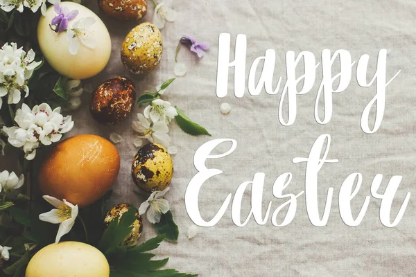 Mutlu Paskalya tebrik kartları. Modern sarı paskalya yumurtalarının üzerine el yazısıyla Mutlu Paskalya yazıları, bahar çiçekleri ve kır kumaşında çiçekler, düz yatak. Güzel kartpostallar, mevsimler selamlar